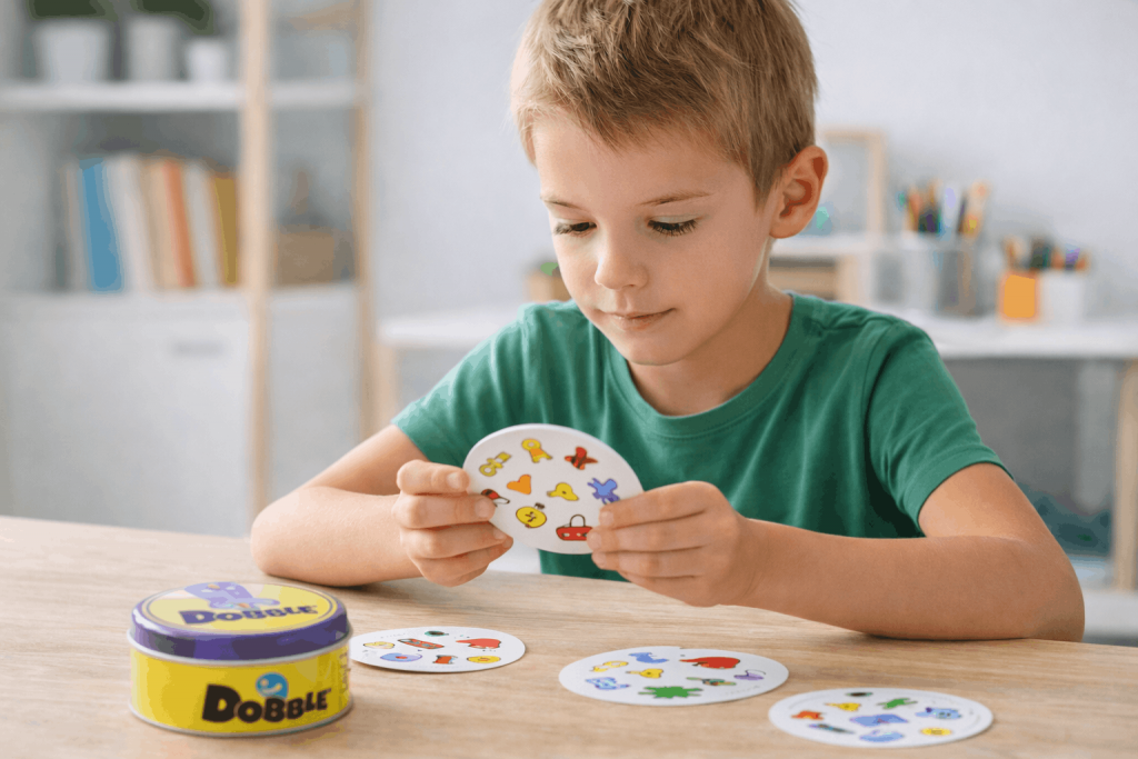 Junge spielt konzentriert Dobble Kartenspiel zur Förderung von Aufmerksamkeit und Konzentration