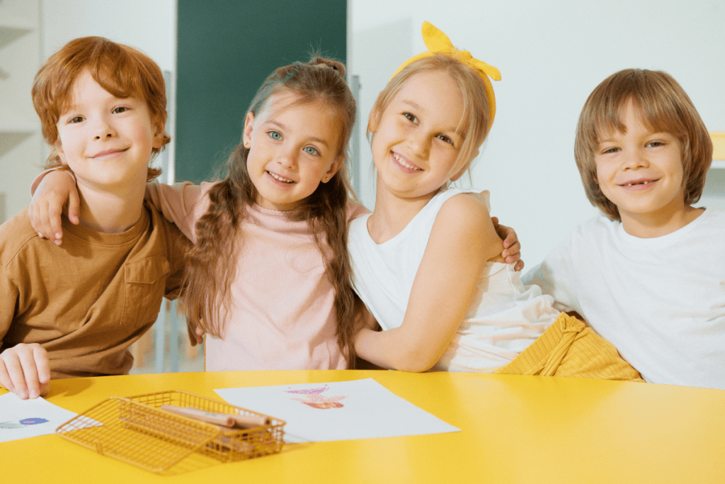 Kinder am Tisch in der Schule Guter Schulstart: Kinder sitzen fröhlich in der Schule am Tisch.